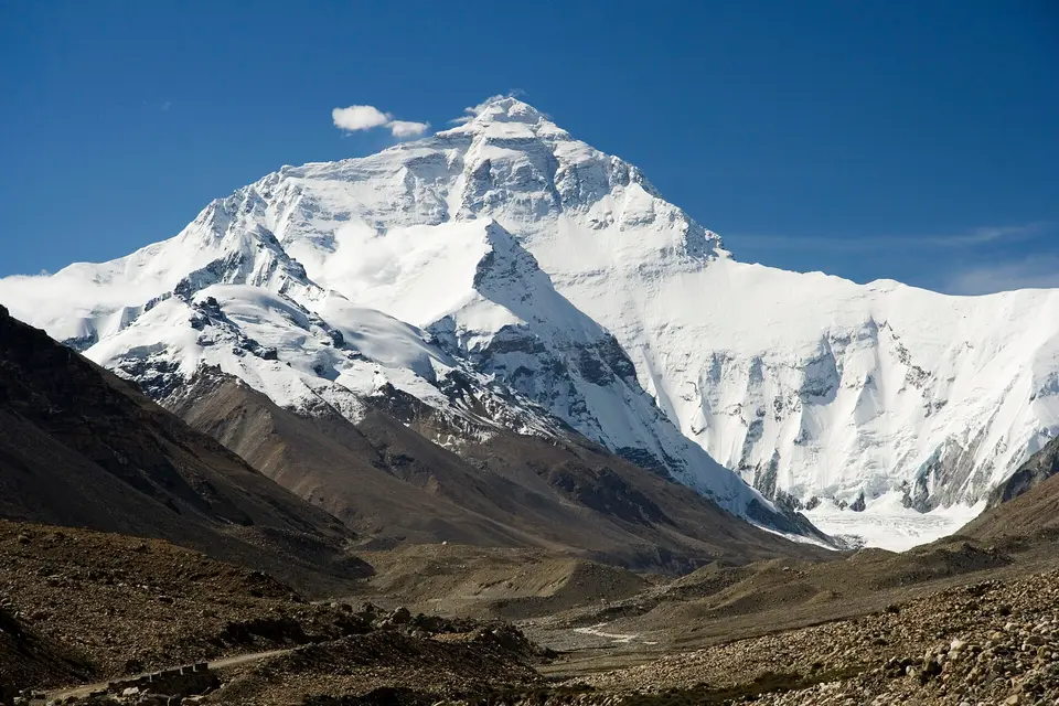 Zasněžená severní stěna Mount Everestu nad suchým skalnatým údolím.
