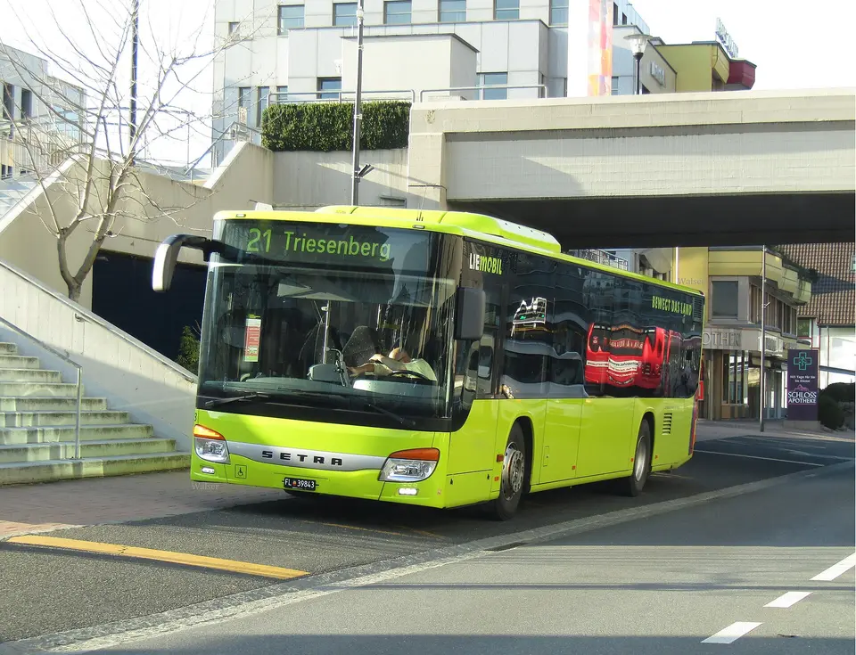 Žlutý linkový autobus LIEmobil jedoucí ulicí ve Vaduzu.
