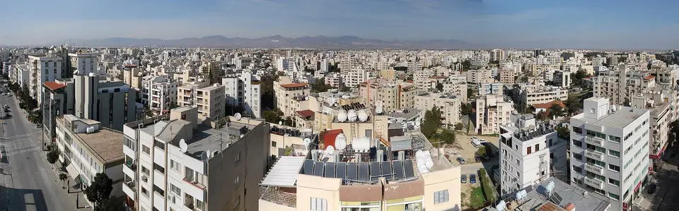 Panorama Nikósie s městskou zástavbou a horami na obzoru.
