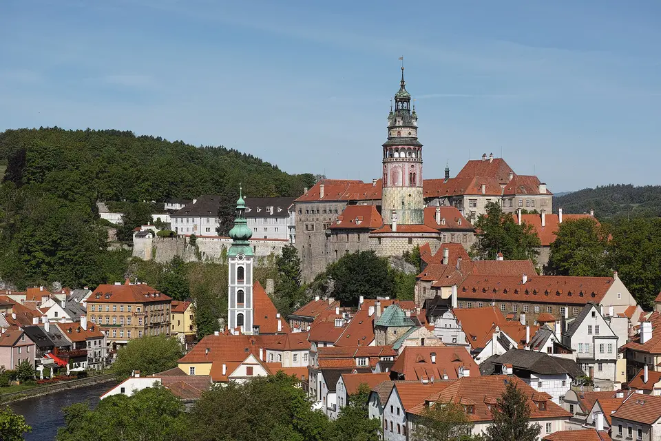 Věž a budovy českokrumlovského zámku nad historickou zástavbou.