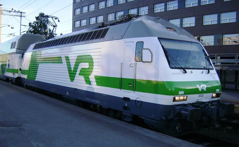 Elektrická lokomotiva s vlakem u nástupiště.