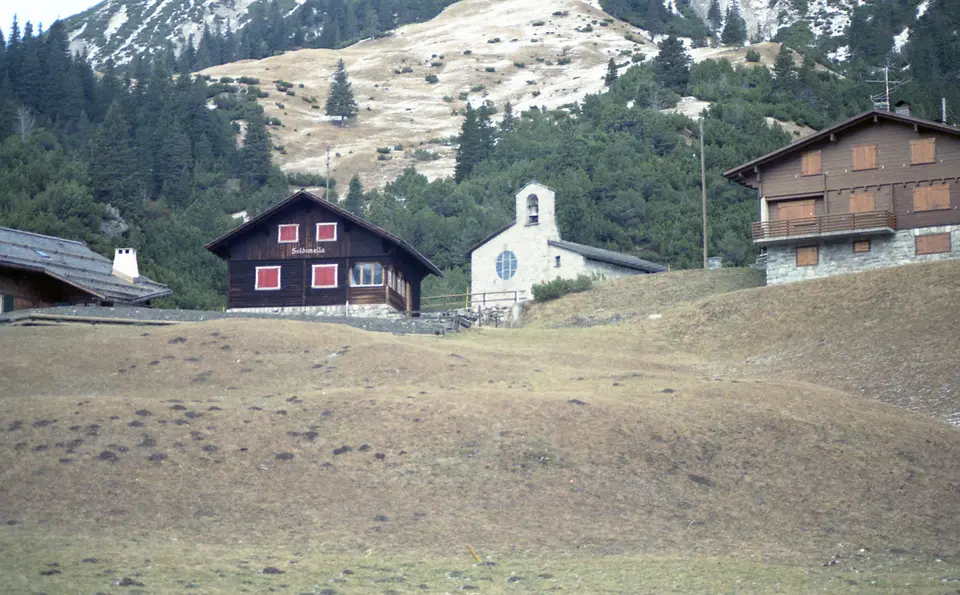 Kaple a horské domy v Malbunu pod alpským svahem.