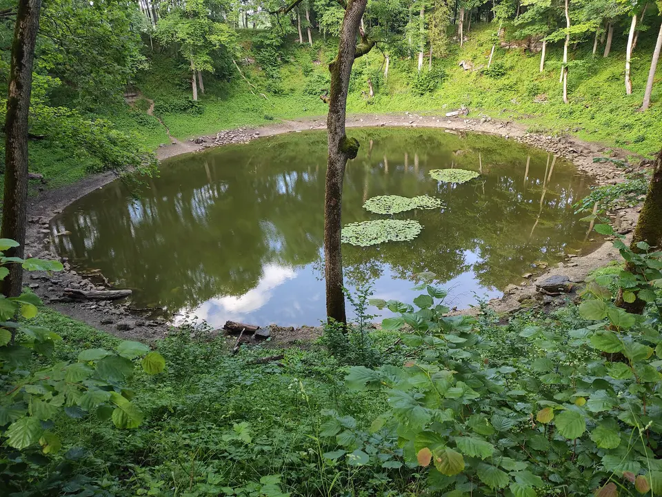 Kruhové jezírko v zalesněném meteorickém kráteru.