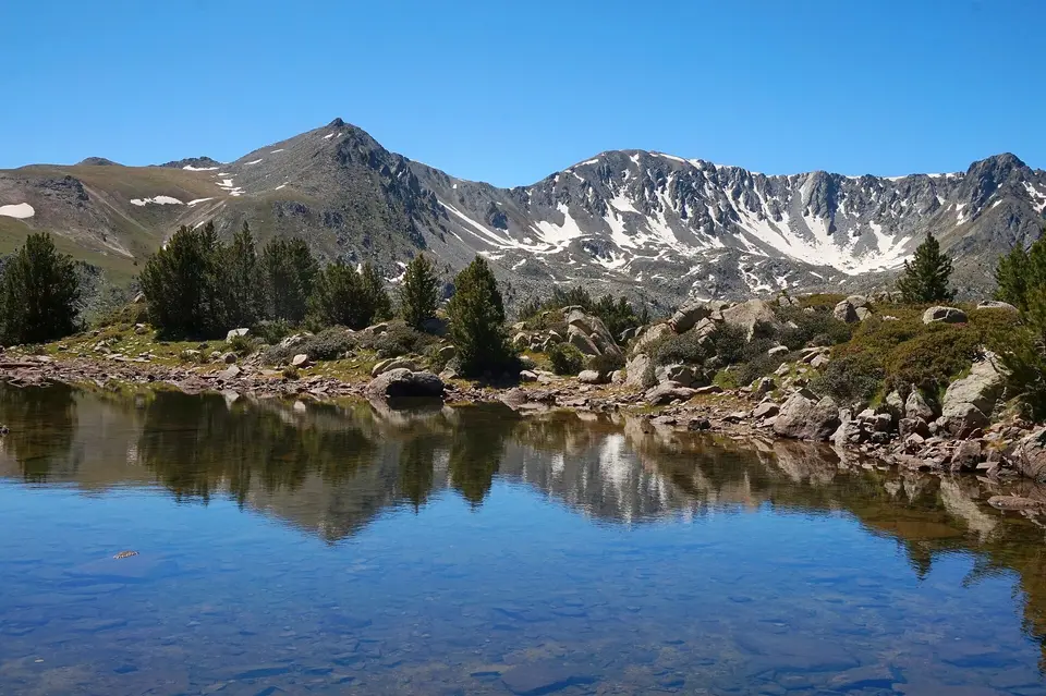 Klidné horské jezero s odrazem skalnatého hřebene.